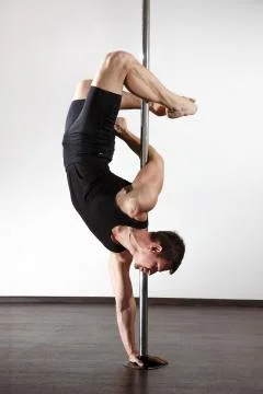 Young strong pole dancer smiling man in black clothes on pylon. White backgro Stock Photos
