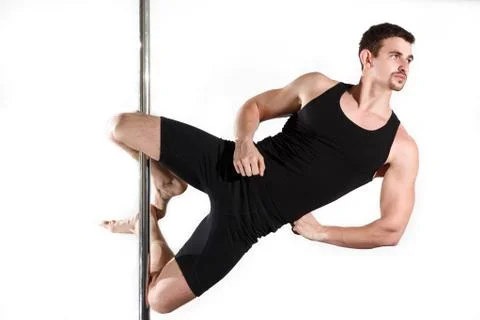 Young strong pole dancer smiling man in black clothes on pylon. White backgro Stock Photos