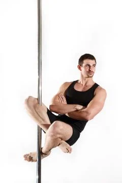 Young strong pole dancer smiling man in black clothes on pylon. White backgro Stock Photos