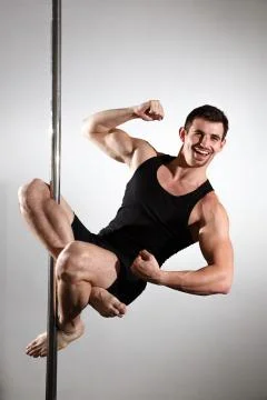 Young strong pole dancer smiling man in black clothes on pylon. White backgro Stock Photos