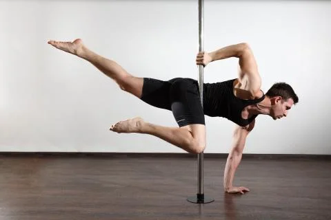 Young strong pole dancer smiling man in black clothes on pylon. White backgro Stock Photos