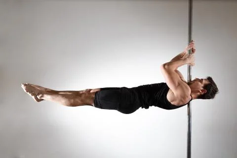 Young strong pole dancer smiling man in black clothes on pylon. White backgro Stock Photos