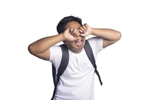 Young student with a backpack crying and rubbing his eyes with both hands i.. Stock Photos