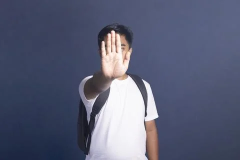 Young student with a backpack making a stop gesture with his hand covering .. Stock Photos