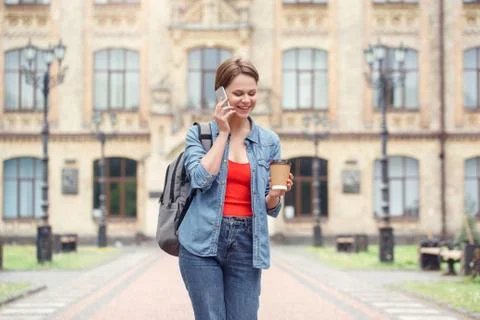Young student with backpack at university campus walking with cup of coffee Stock Photos