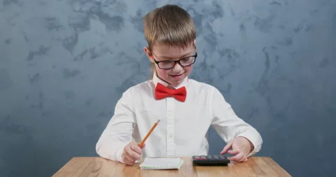 Young student with bow tie uses calculator to present answer 動画素材 304362908