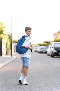 Young student boy with backpack looking at the camera while walking on the Fotos Stock