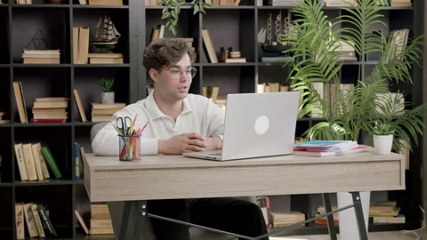 Young student boy sitting at an office table in front of a computer discussing Stock Footage 316090435