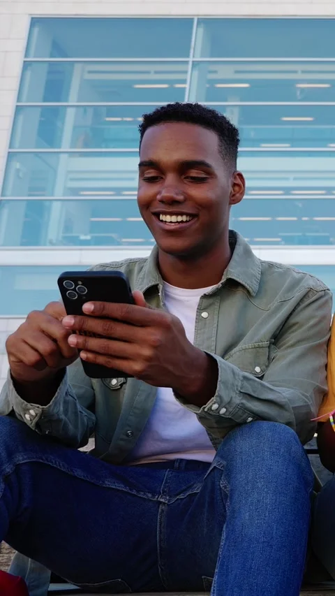 Young student boy using mobile phone sitting at college campus Stock Footage 312265201