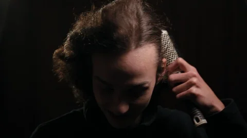 Young student combing his long curly hair with hairbrush in the dark room Stock Footage 99050572