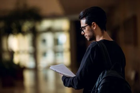 Young student of computer science consults some papers illuminated by the light Stock Photos