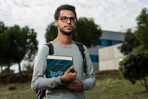 Young student of computer science poses with a robotics book next to one of the Stock Photos