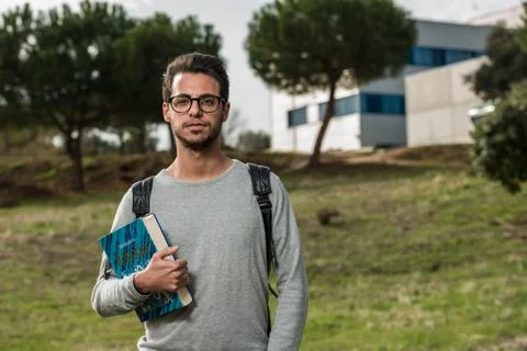Young student of computer science poses with a robotics book next to one of the Stock Photos