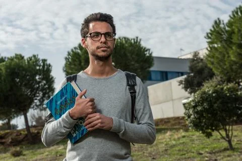 Young student of computer science poses with a robotics book next to one of the Stock Photos