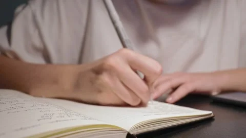 Young student doing homework write in notebook with black pen on white paper Stock Footage 163252032