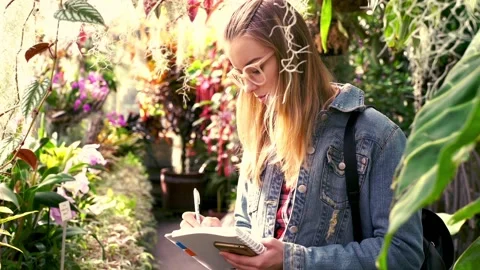 Young student doing notes in botanic garden Видео 85802593