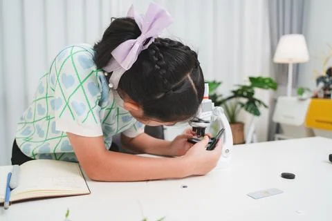 Young student examining slide through microscope showing STEM curiosity and Stock Photos