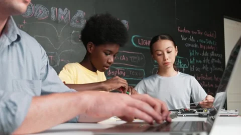 Young student fixing controller while teacher programming code. Edification Stock Footage 274385983