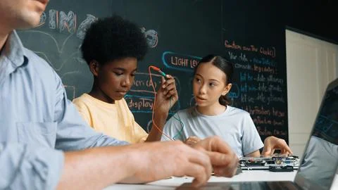 Young student fixing controller while teacher programing code. Edification. Foto stock