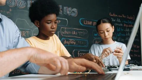 Young student fixing controller while teacher programing code. Edification. Foto stock