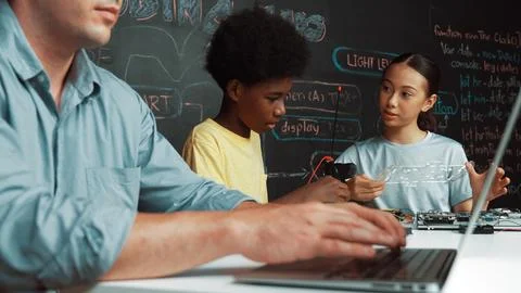 Young student fixing controller while teacher programing code. Edification. Foto stock