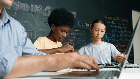 Young student fixing controller while teacher programing code. Edification. Foto stock
