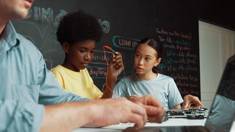 Young student fixing controller while teacher programing code. Edification. Stock Photos