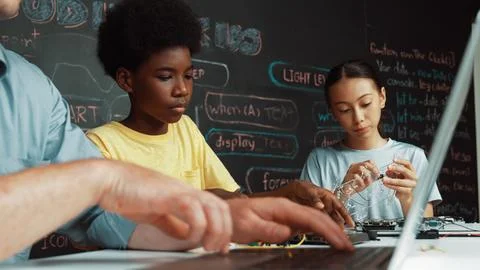 Young student fixing controller while teacher programing code. Edification. Foto stock