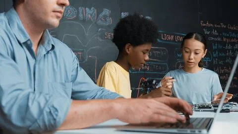 Young student fixing controller while teacher programing code. Edification. Foto stock