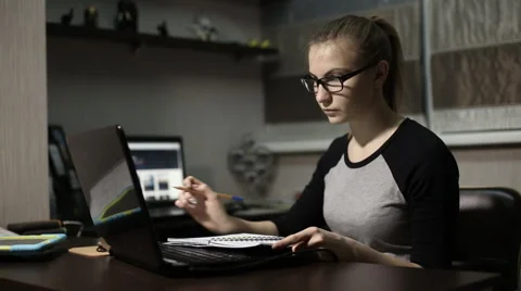 Young student in front of a laptop to take notes in a notebook at night Stock Footage 60052171