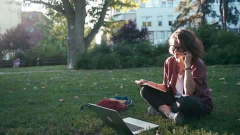 Young student girl making notes in her notebook and taking a phone call Stock Footage 138296361