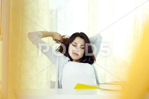Young student girl stretching herself while doing homework Stock Photos