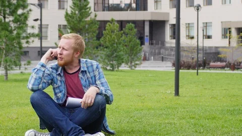 A young student goes to the background of the university talking on the phone Vidéo 107382461