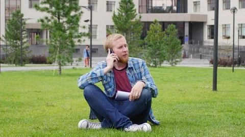 A young student goes to the background of the university talking on the phone Видео 107382620