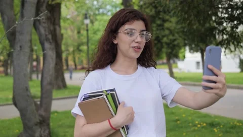 Young student has video chat online call near college campus, outdoors. Video stock 194637735
