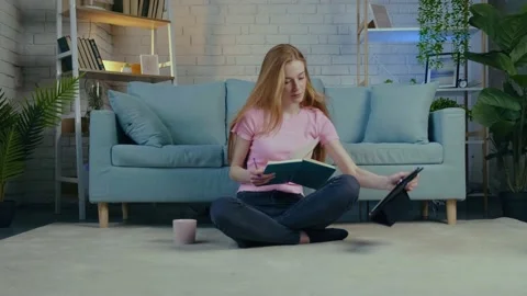 Young student is having online lessons on the floor using a tablet and drinking Video stock 153087057