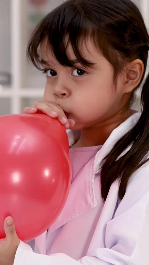Young Student in Lab Coat Blowing Up a Red Balloon Stock Footage 344105058