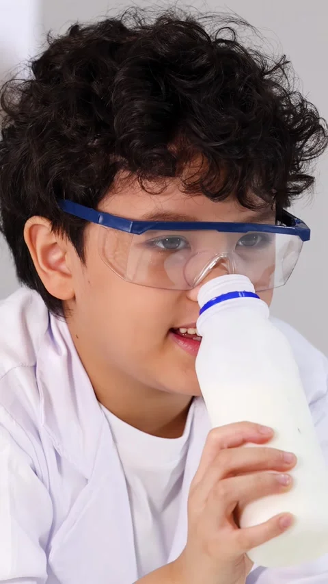 Young Student in Lab Coat Smelling Milk Bottle During Science Experiment Stock Footage 337752170