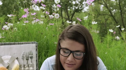 Young student learning with a book in the park, while having a picnic in spring. Stock Footage 199632298