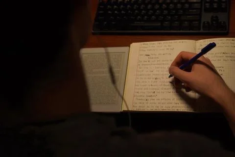 A young student performs an English language assignment in writing in a not.. Stock Photos