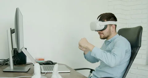 Young student playing in virtual games. Cheerful brunette man in a blue shirt in Stock Footage 215959429