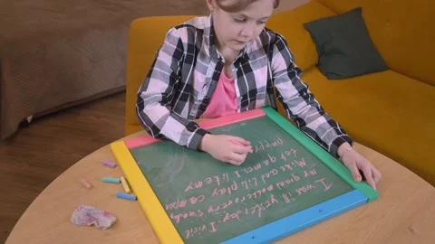 Young student practicing writing on small chalkboard 库存影片 315876407