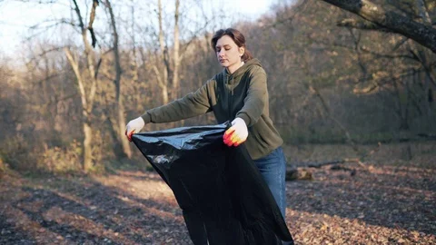 A young student preparing to collect garbage in the woods, opens a large black Video stock 124155811