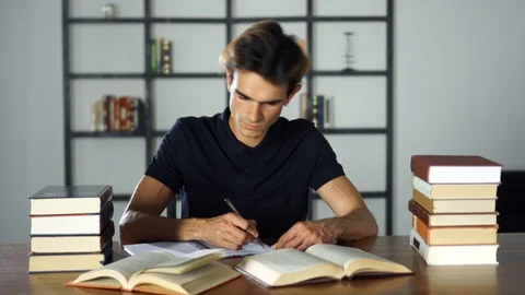 Young student preparing for lessons in the library. Writting notes, reading Stock Footage 93241130