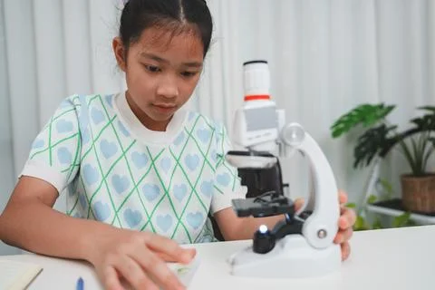 Young student preparing slide for microscope study demonstrating STEM curiosi Stock Photos