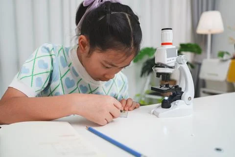 Young student preparing slide for microscope study demonstrating STEM curiosi Stock Photos