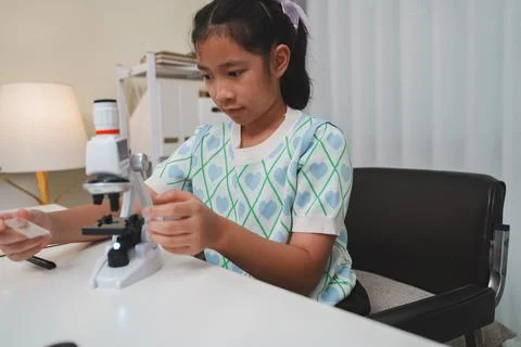 Young student preparing slide for microscope study demonstrating STEM curiosi Stock Photos