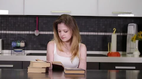 Young student reading books in a kitchen Stock Footage 49930331