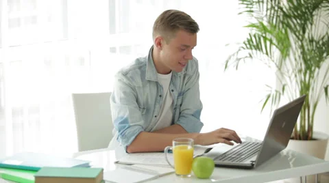 Young student sitting at table using laptop and drinking juice Stock Footage 27691903