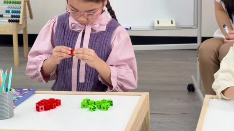 Young Student Solving Math Problems with Counting Blocks in Classroom Stock Footage 321443970
